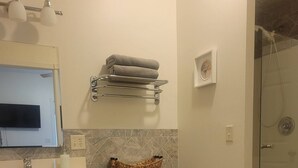 Casa de banho com sanita, lavatório e chuveiro.