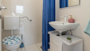 Une salle de bain avec des toilettes, un lavabo et un rideau de douche.