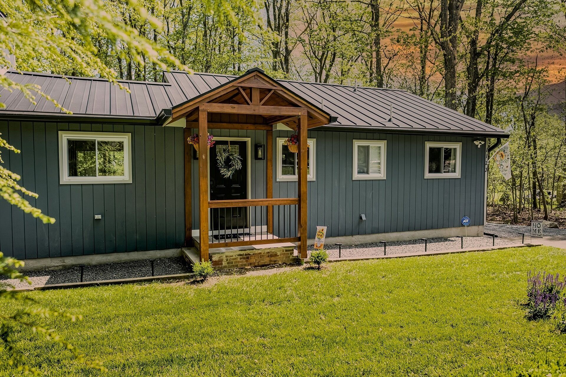 Ein zweistöckiges Haus mit Veranda, einem kleinen Anbau aus Backsteinen und einem gepflegten Rasen.