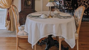 Ein Essbereich mit rundem Tisch, Stühlen, einer Uhr und einer Kandelaber.