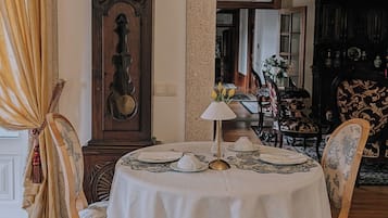 Un comedor con una mesa redonda, sillas, un reloj y una araña.