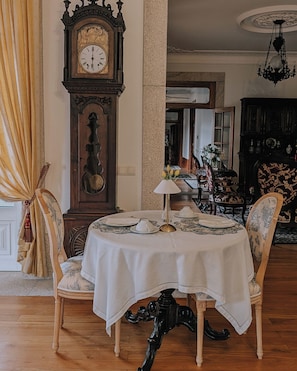 A dining area with a round table, chairs, a clock, and a chandelier.
