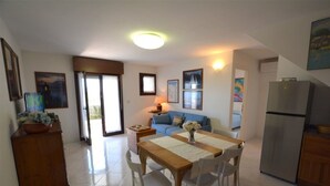 A spacious living area with a dining table, sofa, and kitchen area.