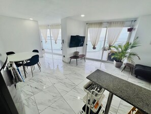 Una sala de estar moderna con comedor, ventanas amplias y televisor de pantalla plana.