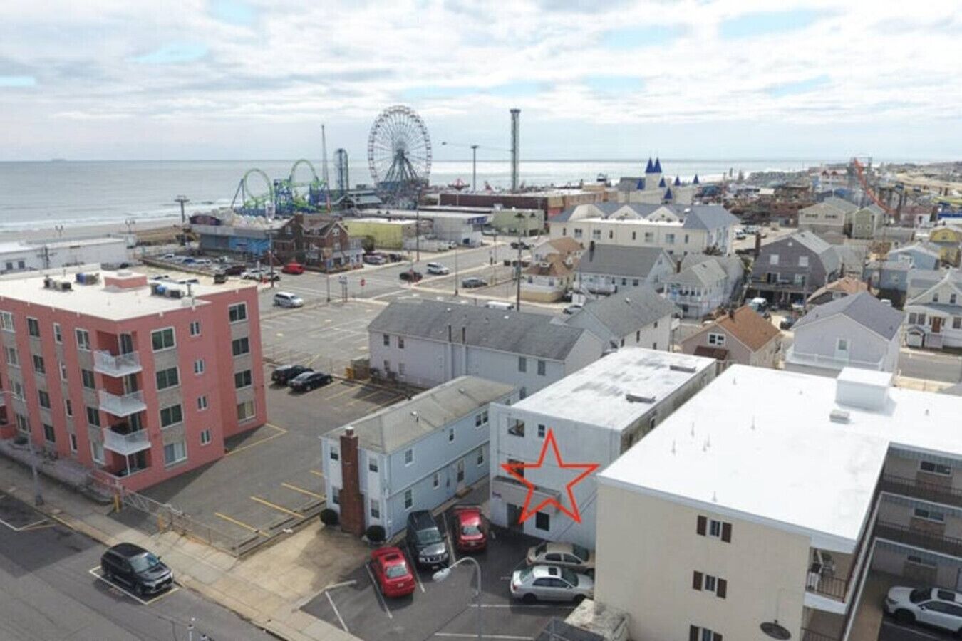 A coastal town with a prominent Ferris wheel, various buildings, and a parking lot.