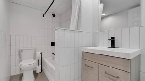 Un baño moderno con inodoro, ducha y tocador con cajones.