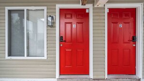 Un edificio de dos plantas con dos puertas rojas, cada una marcada con un número.