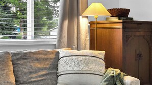 A corner sofa with a throw blanket and a lamp on a wooden cabinet.