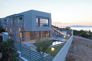 Uma casa moderna de dois andares com fachada de pedra, varanda e piscina.
