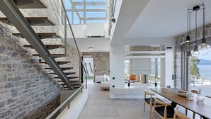 A modern interior with a staircase, a dining area, and a view of the outdoors. - Design villa with immaculate views in Theologos (Theologos)