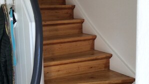 Una escalera de madera con pared blanca y barandilla negra.