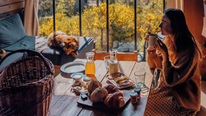 A cozy room with a large window, wooden furniture, and a breakfast setup on a wooden table. - Nutchel Cosy and Nature Cabin for 4 (Martelange)