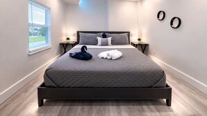 A modern bedroom with a large bed, bedside tables, a window, and a view of the outdoors. - Daytona Double Delight (Daytona Beach)