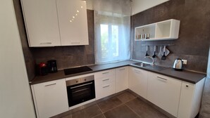 Eine moderne Küche mit weißen Schränken, einer Edelstahl-Spüle und einem eingebauten Backofen.