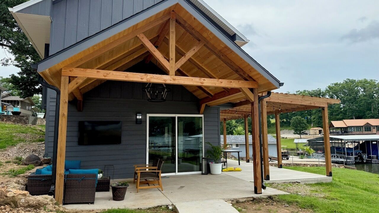 Une maison moderne dotée d’un patio couvert, d’un espace salon extérieur et offrant une vue sur un lac.