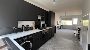 A modern kitchen with black cabinets, a built-in dishwasher, and a large window. - Nottingham 2-bed House, Sleeps 4, Pet Friendly (Nottingham)