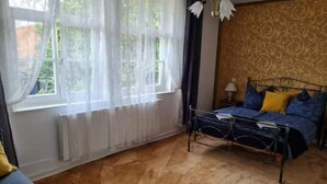 A bedroom with a bed, a radiator, a window with sheer curtains, and a patterned wall. - Golden apartment on the estate (Nordstemmen)