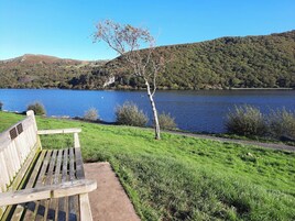Un banco con vista a un lago y una colina boscosa al fondo.