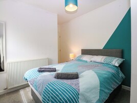 Un dormitorio con cama, lámpara de noche y radiador.