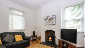 A living room with a fireplace, a sofa, a TV, and a window with blinds.