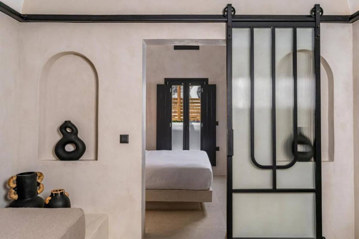 A bedroom with a bed, a sliding door, and a wall-mounted shelf with decorative items.