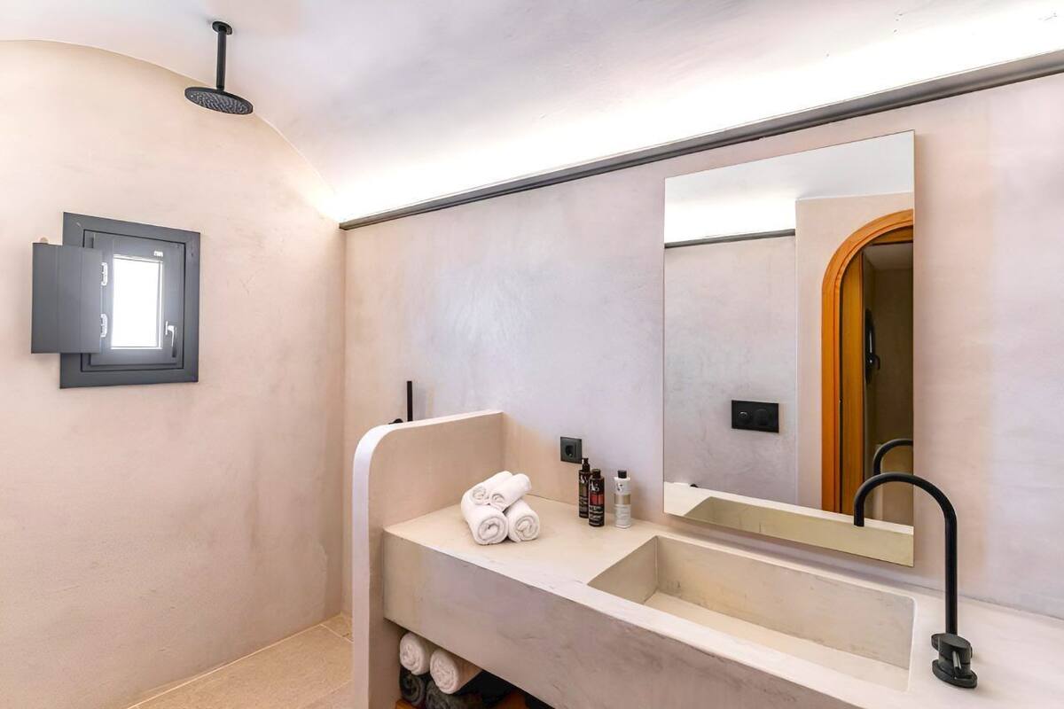 A modern bathroom with a large sink, a mirror, and a towel rack.