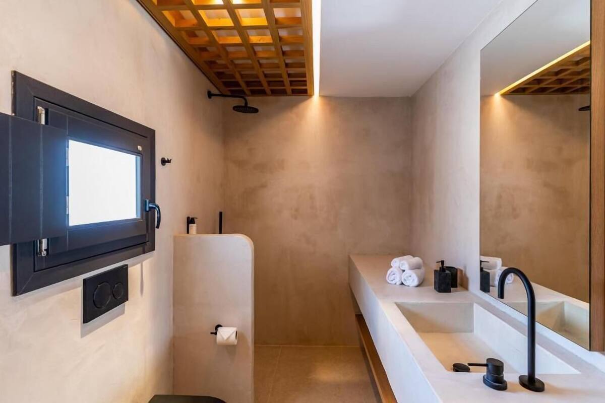 A modern bathroom with a large mirror, a built-in sink, and a shower area.