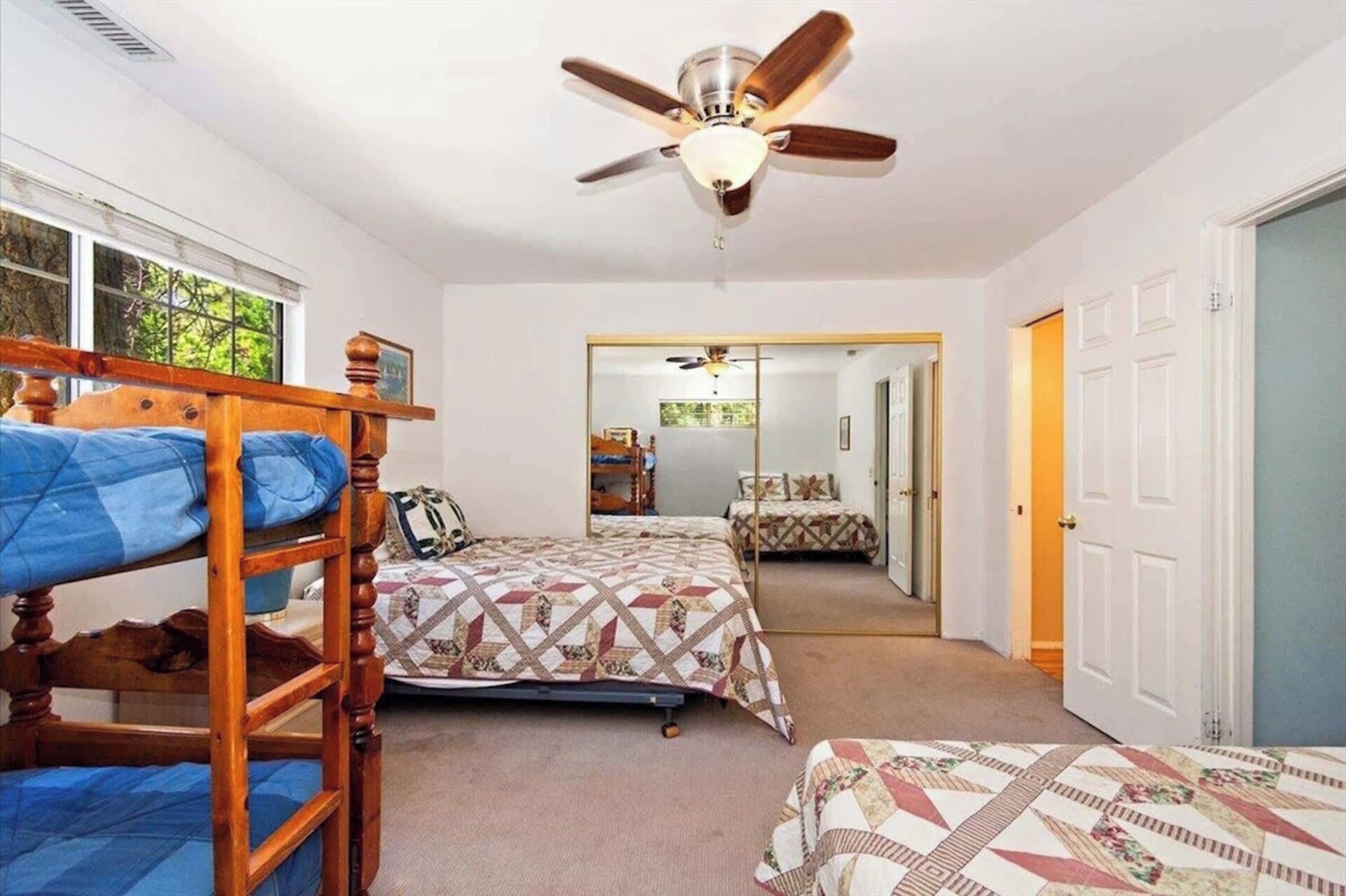 A bedroom with bunk beds, a ceiling fan, and a view of a hallway.