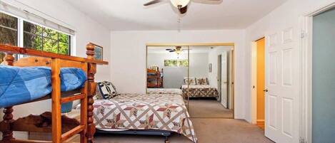 A bedroom with bunk beds, a ceiling fan, and a view of a hallway.