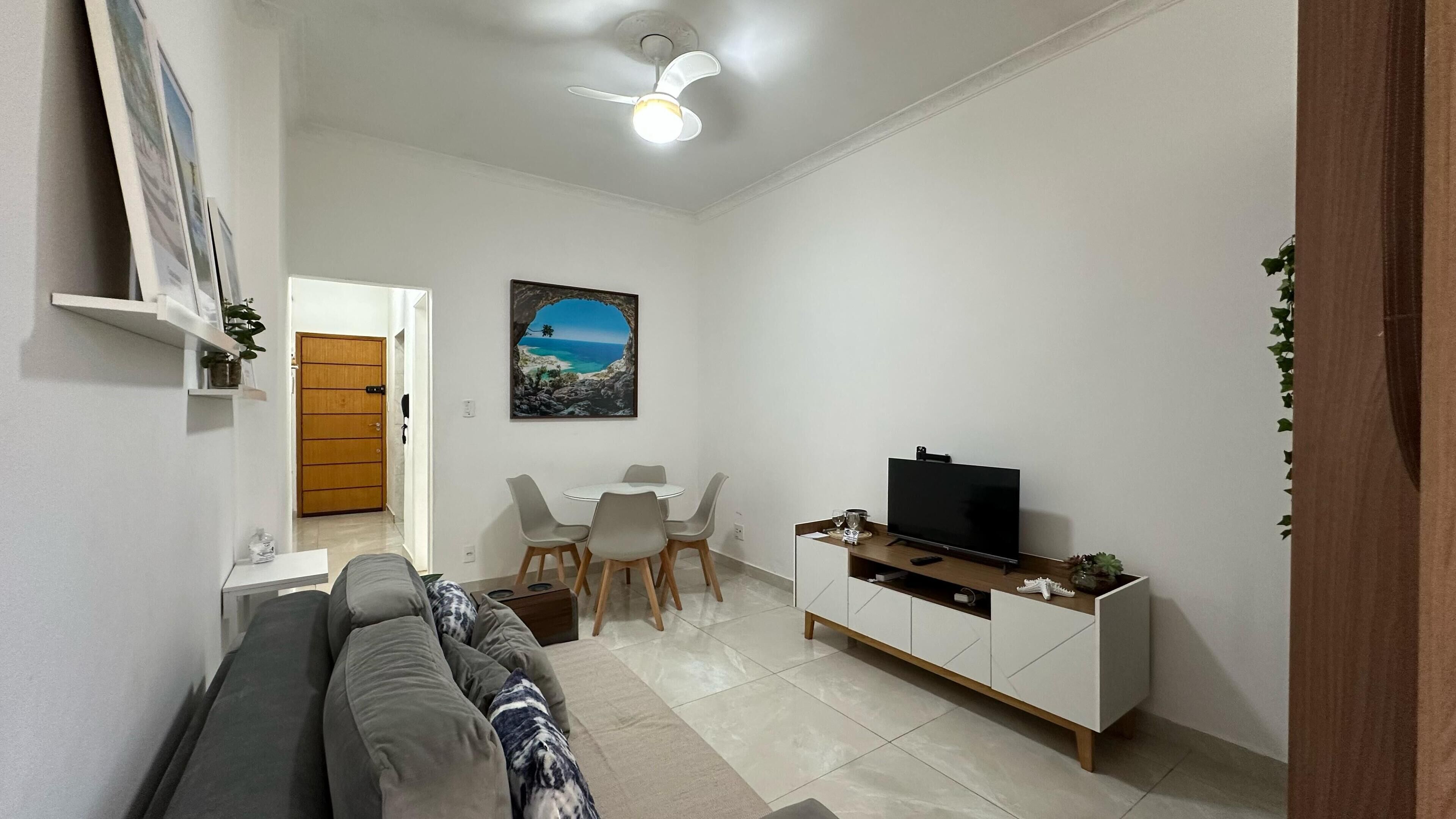 Ein Wohnzimmer mit Sofa, Fernseher und Essbereich.