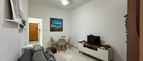 Ein Wohnzimmer mit Sofa, Fernseher und Essbereich.