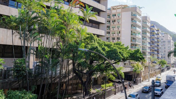 A multi-story building with balconies, surrounded by lush greenery and parked vehicles. - SUH Botafogo 04 Pão de Açúcar View (Rio de Janeiro)