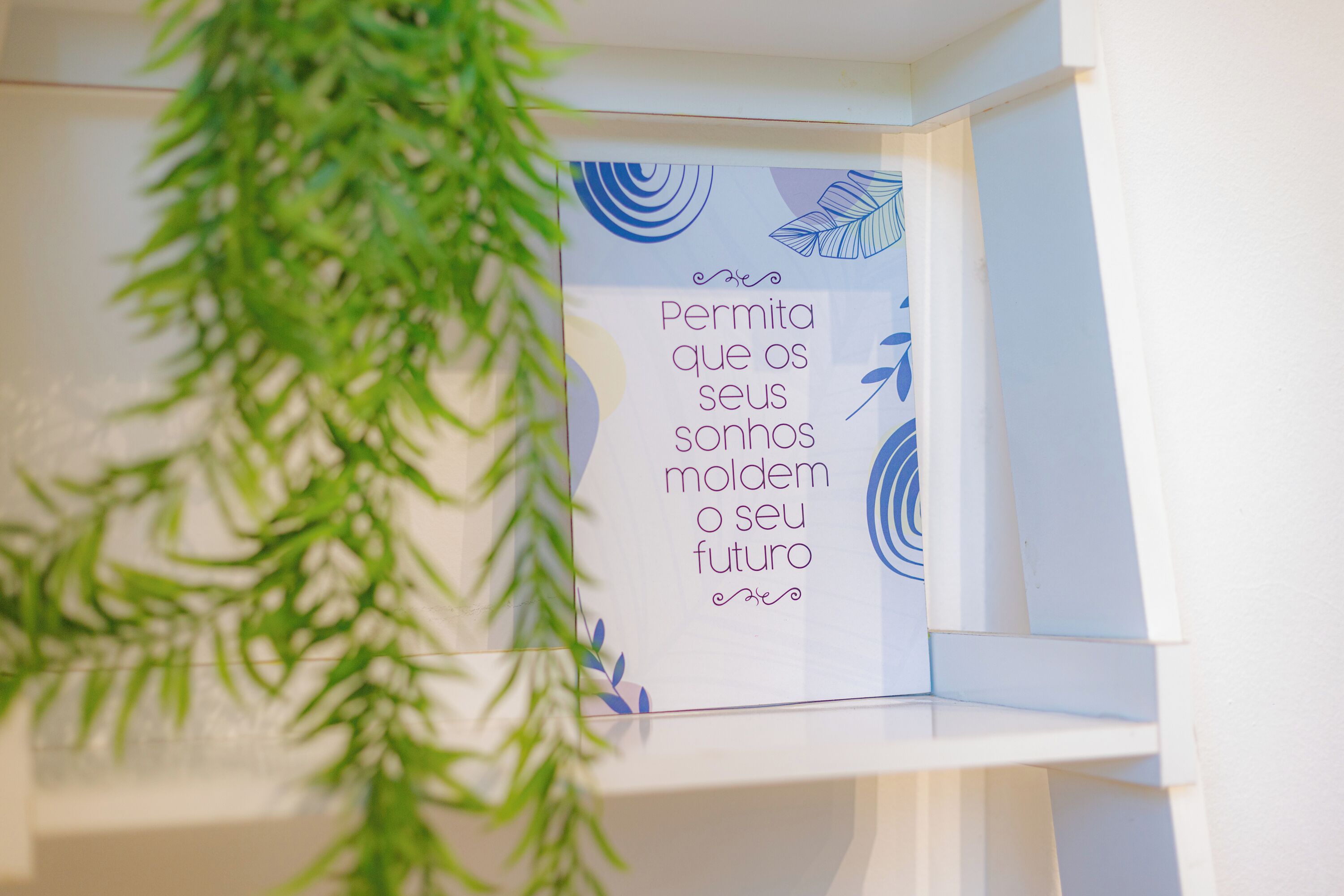 A framed inspirational quote on a white shelf.