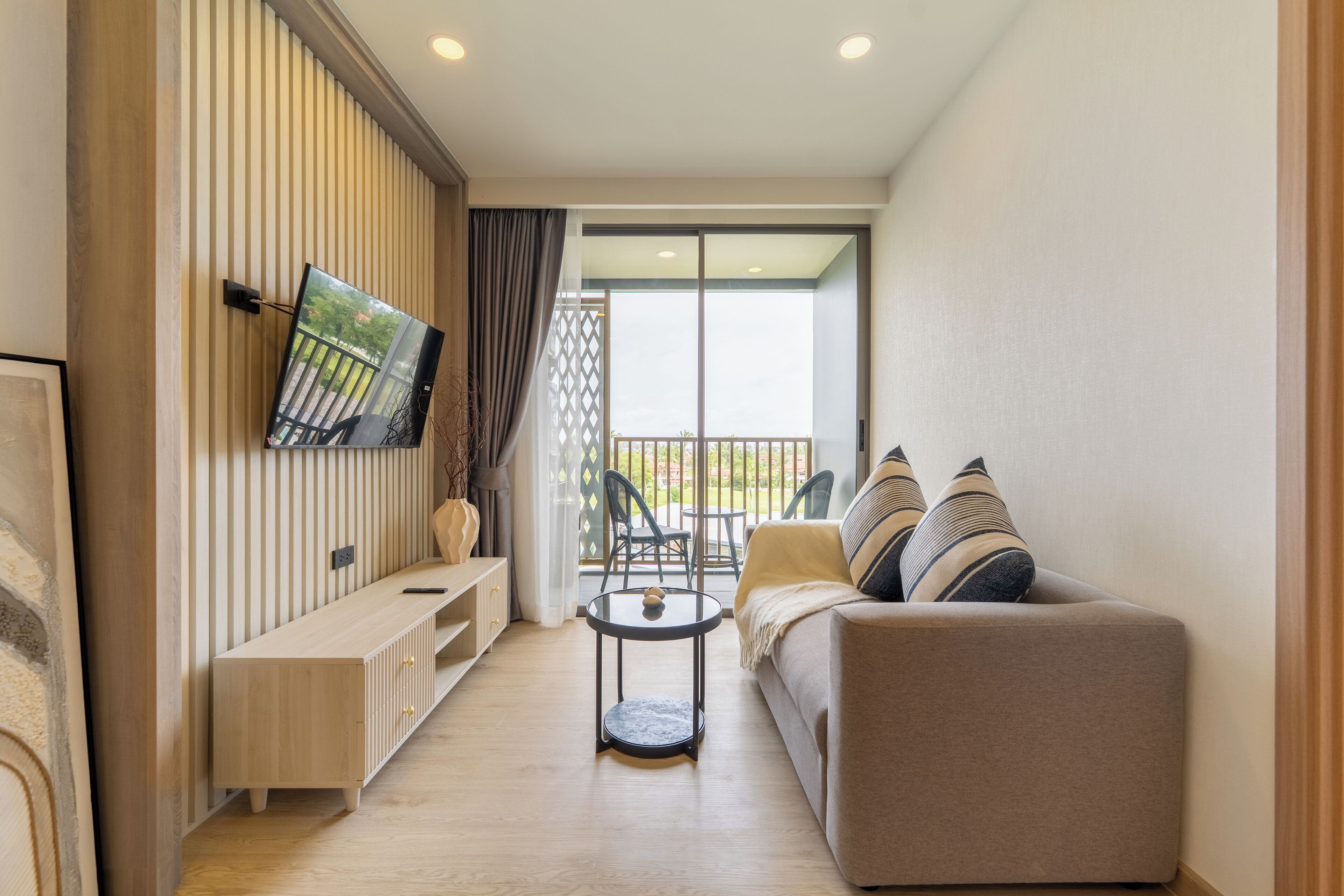 A modern living room with a sofa, a coffee table, and a TV mounted on the wall.