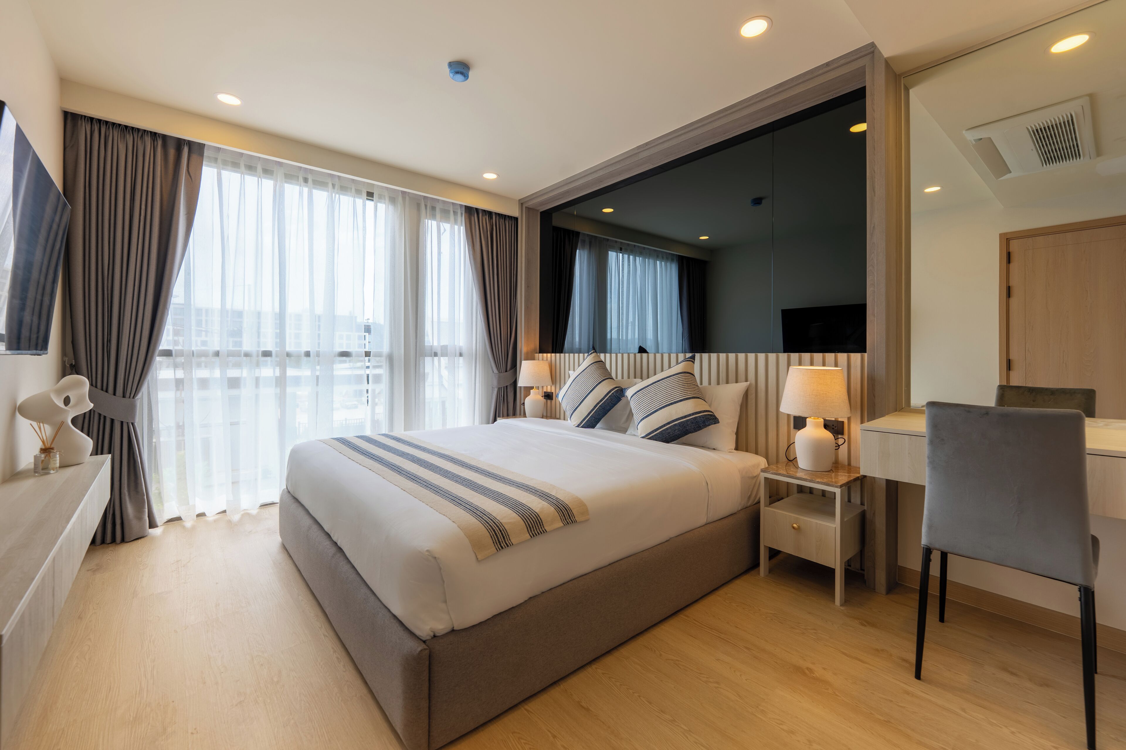 A modern hotel room with a large bed, a desk, and a TV.
