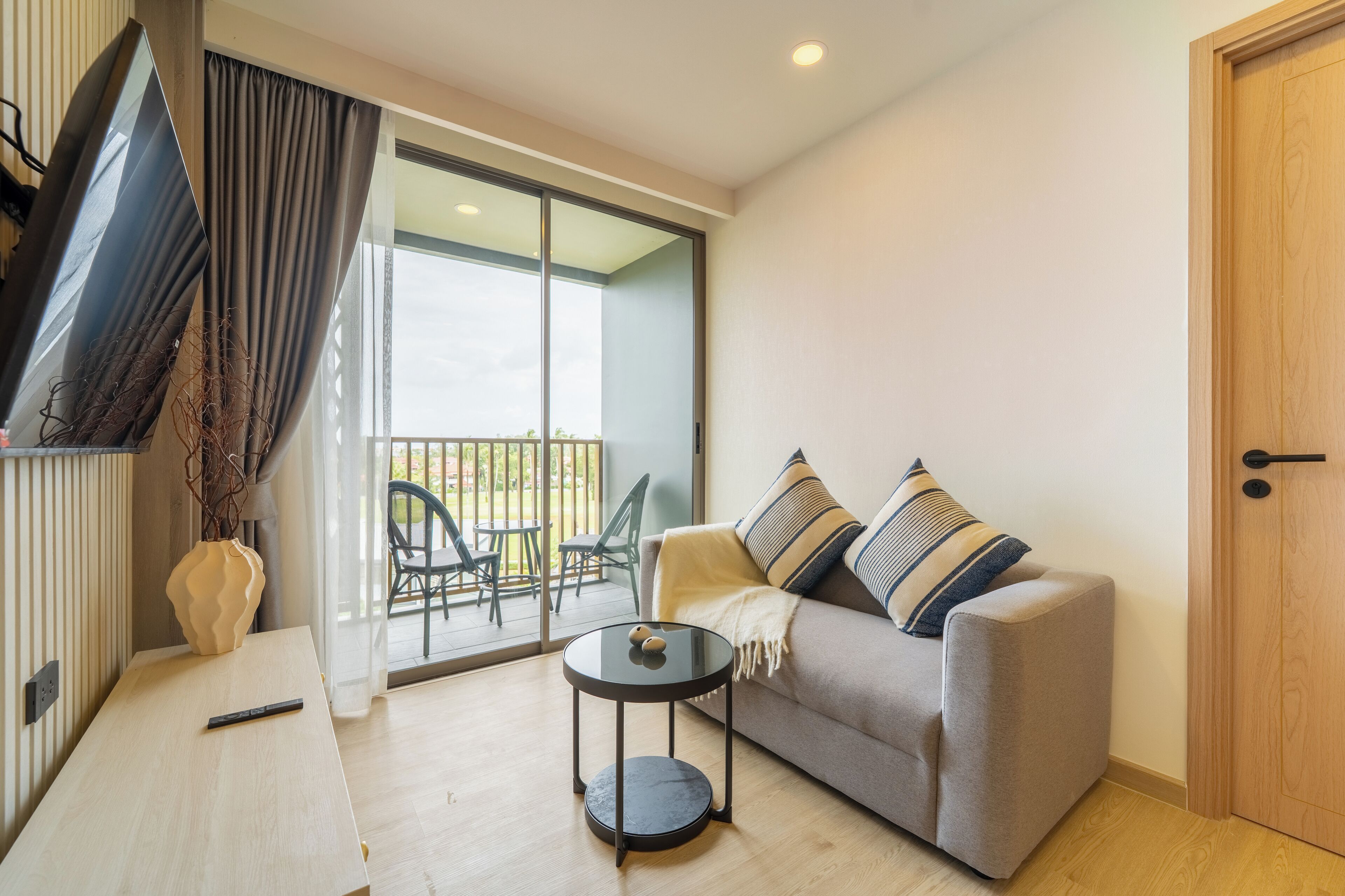 A modern living room with a sofa, a small round table, and a TV mounted on the wall.