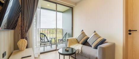 A modern living room with a sofa, a small round table, and a TV mounted on the wall.