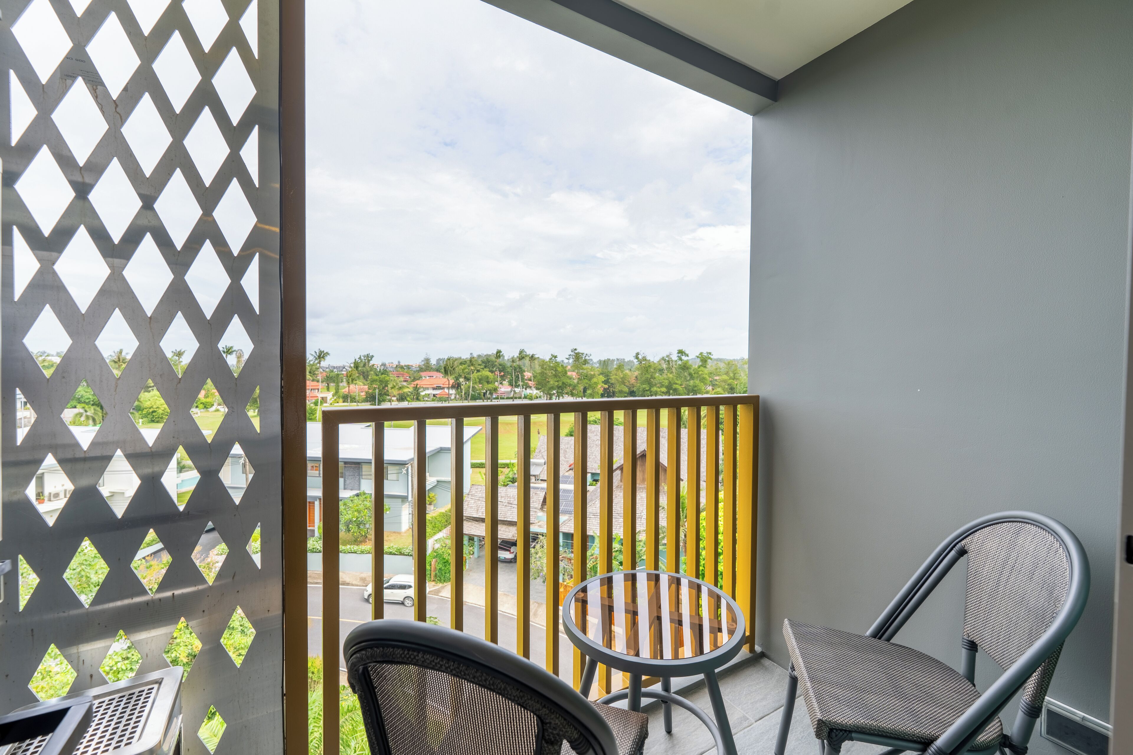 Un balcon donnant sur un quartier résidentiel, une petite table ronde et deux chaises.