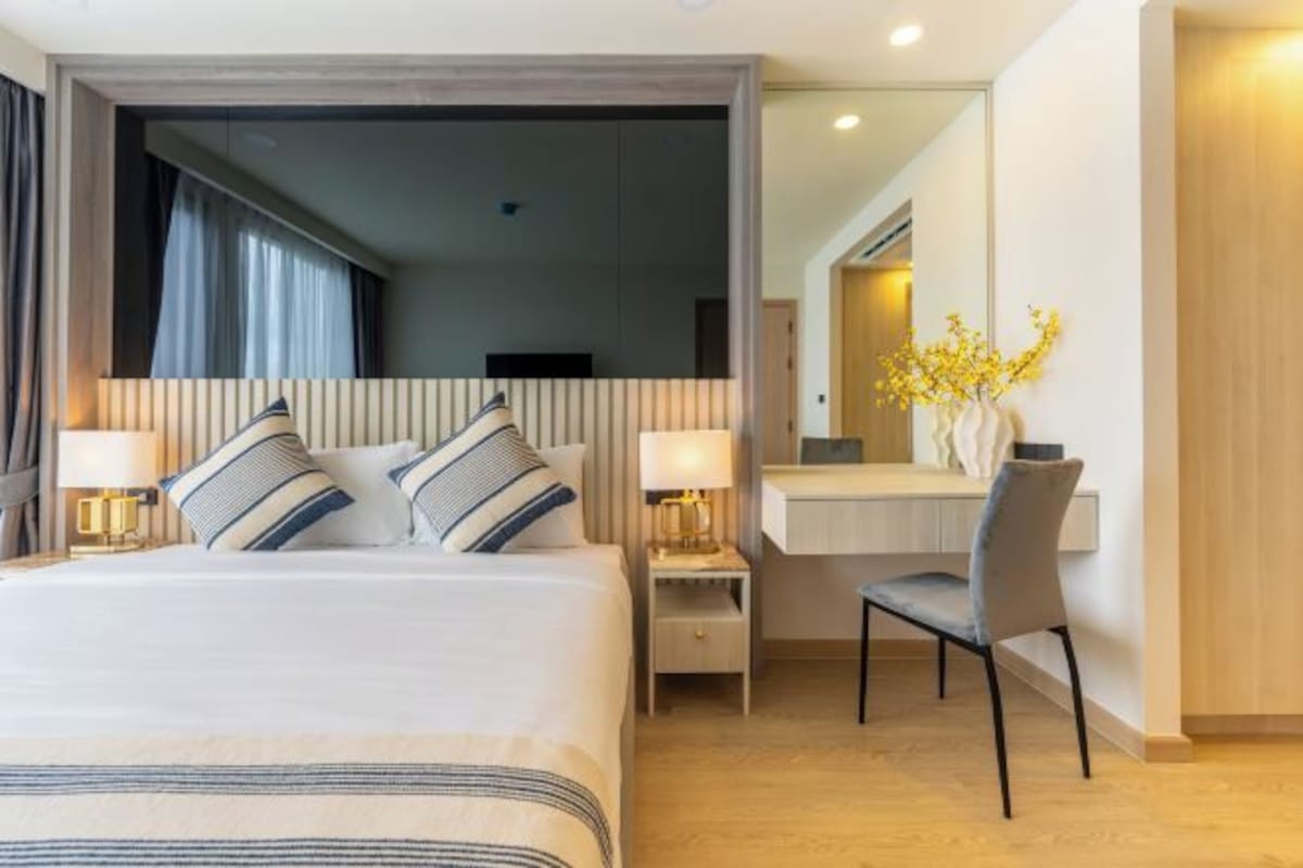A hotel room with a bed, bedside tables, a desk, and a chair.