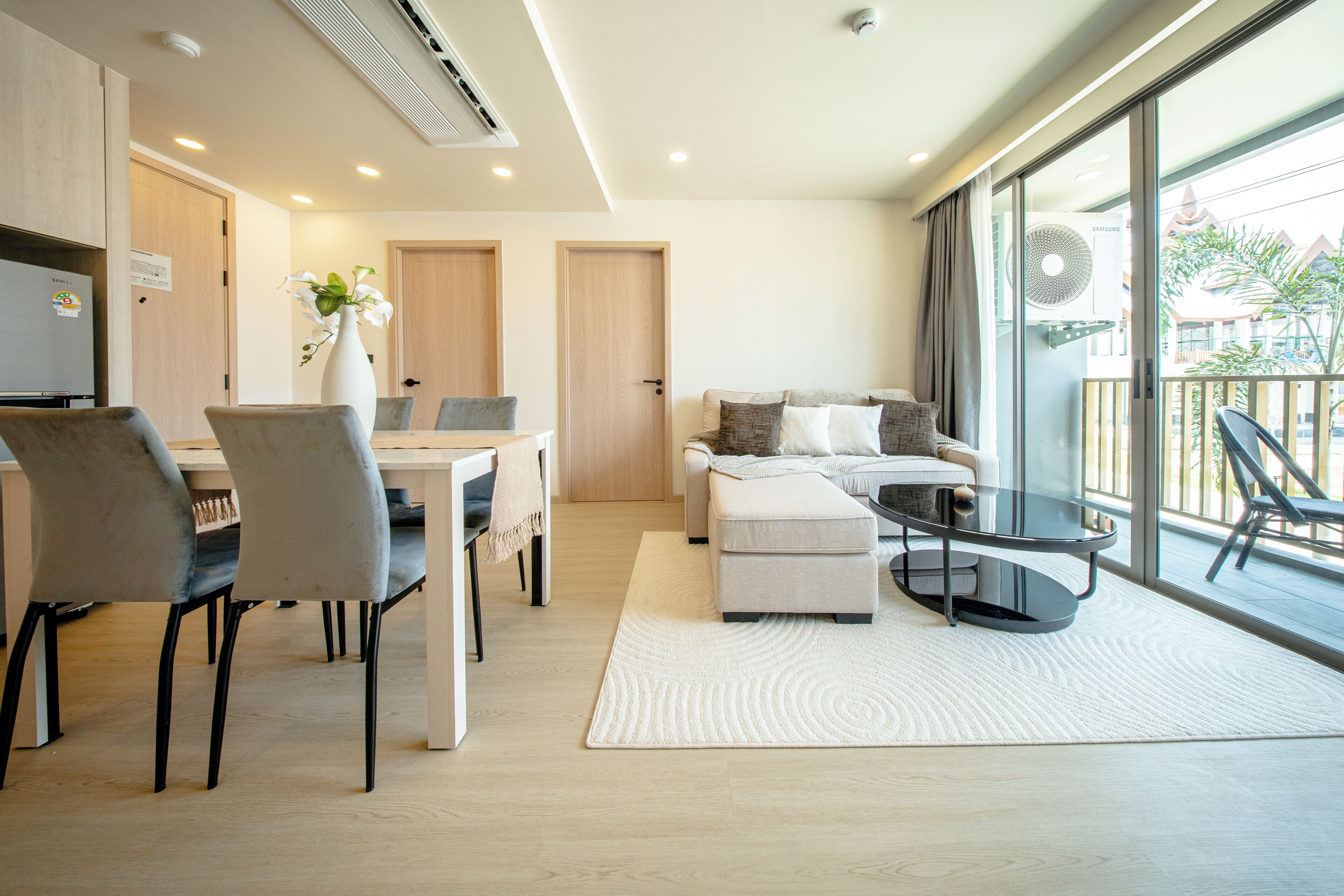 A modern living room with a sofa, a glass coffee table, and a dining area with chairs and a table.