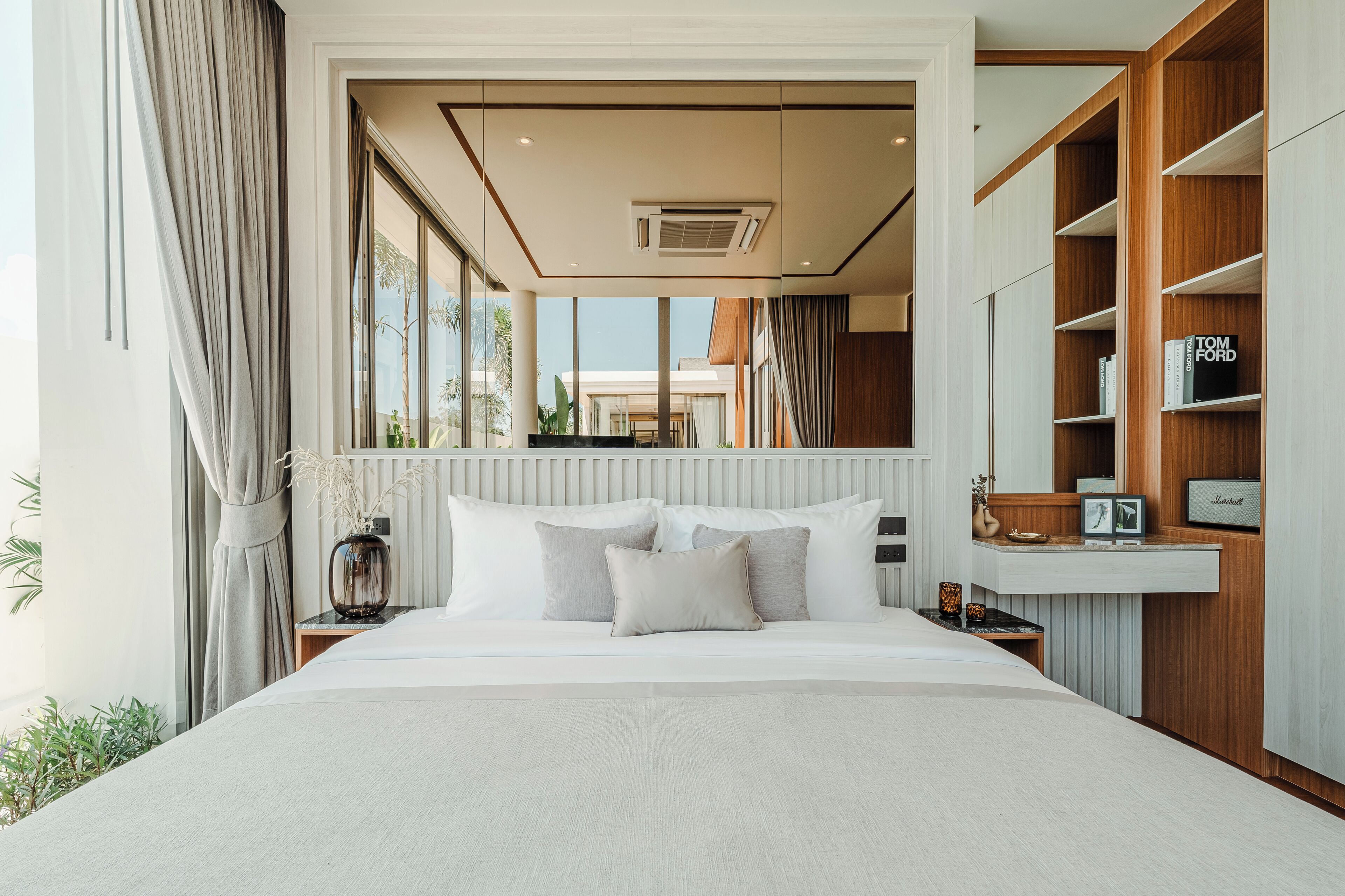 A modern bedroom with a large bed, a built-in wardrobe, and a view of the outdoors.