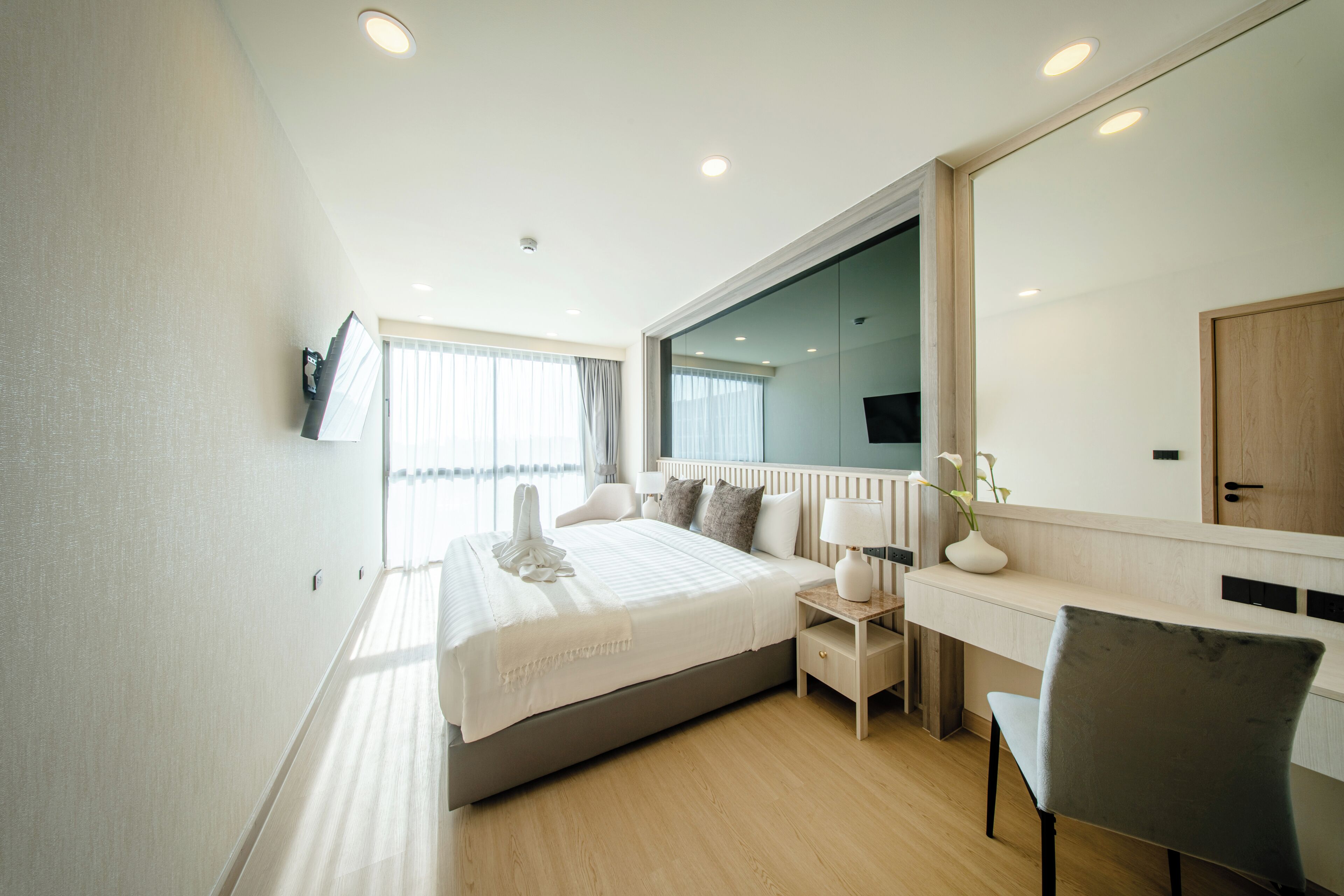 Une chambre d’hôtel moderne avec un grand lit, des tables de chevet, un bureau et une chaise.