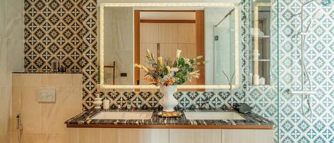 Une salle de bain avec des carreaux à motifs, un meuble-lavabo en bois, un évier, des toilettes et un miroir.
