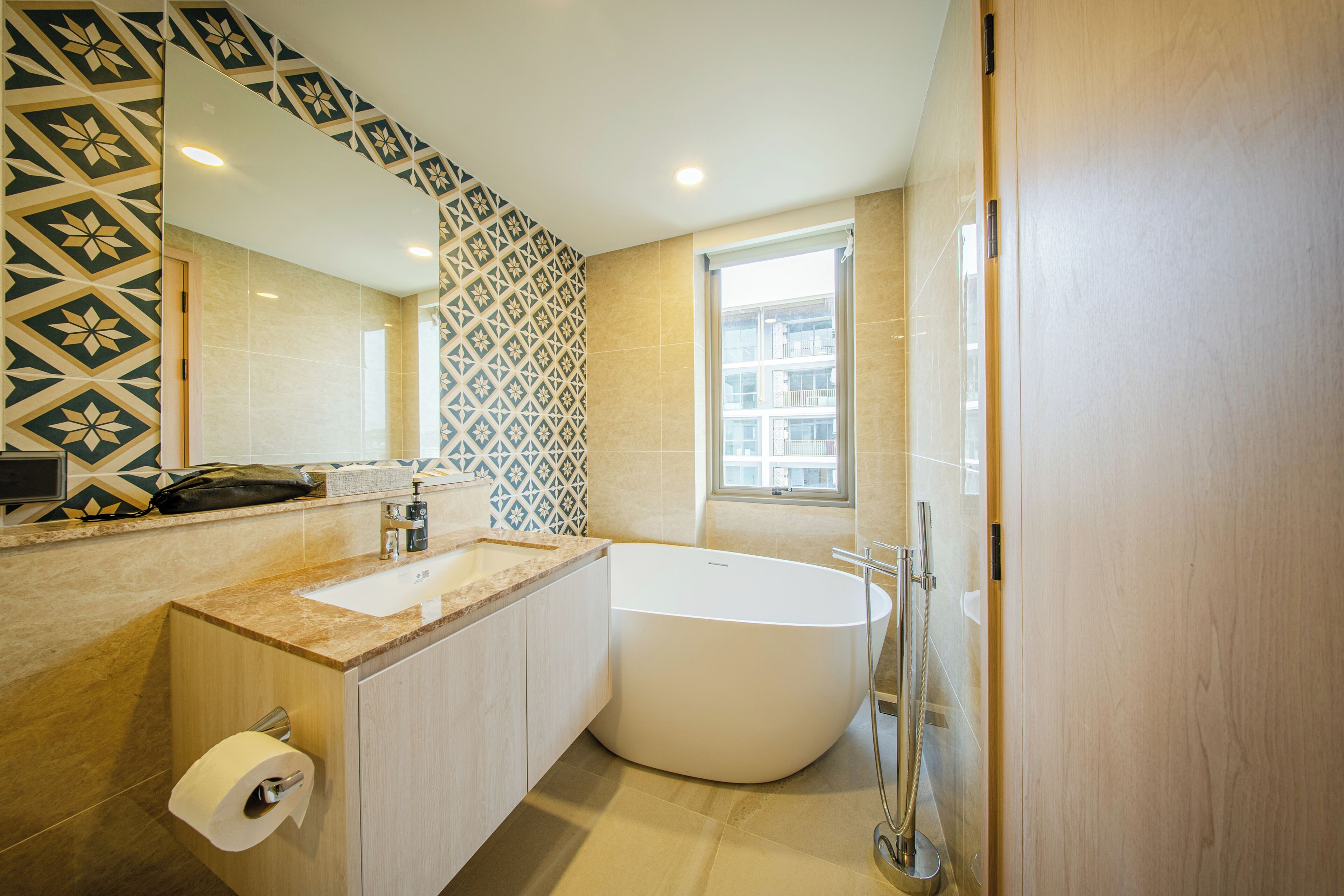 A modern bathroom with a large bathtub, a sink, a toilet, and a mirror.