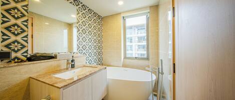 A modern bathroom with a large bathtub, a sink, a toilet, and a mirror.