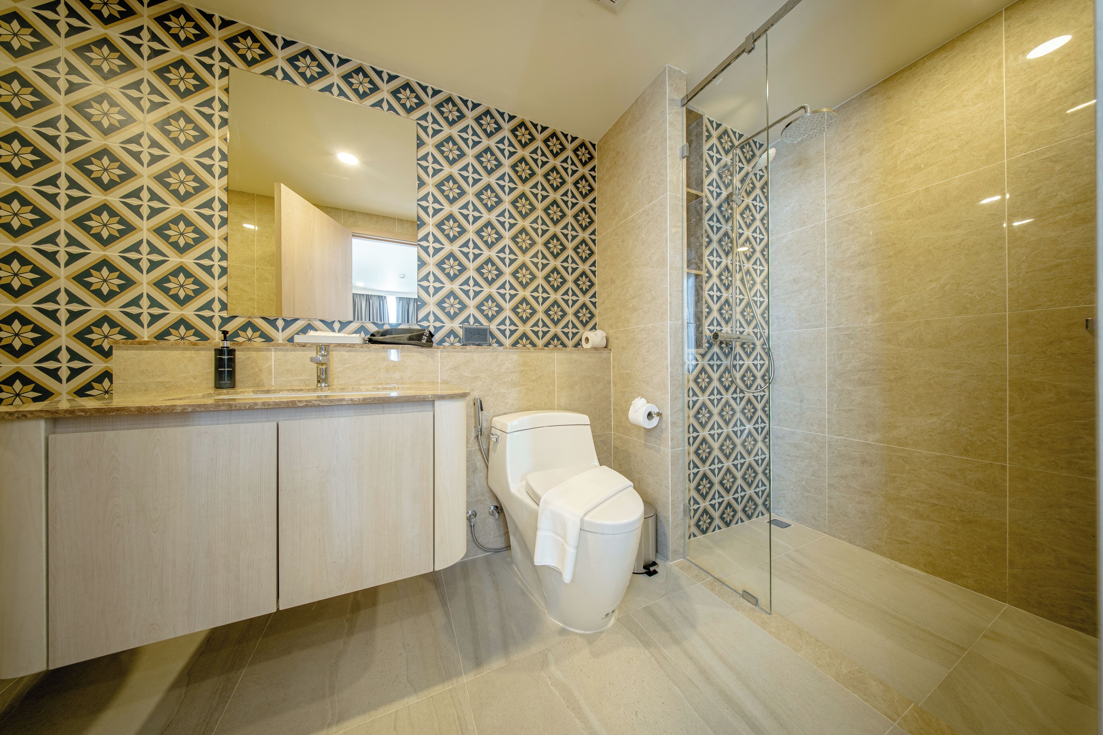 A modern bathroom with a patterned wall, a glass shower enclosure, and a toilet.