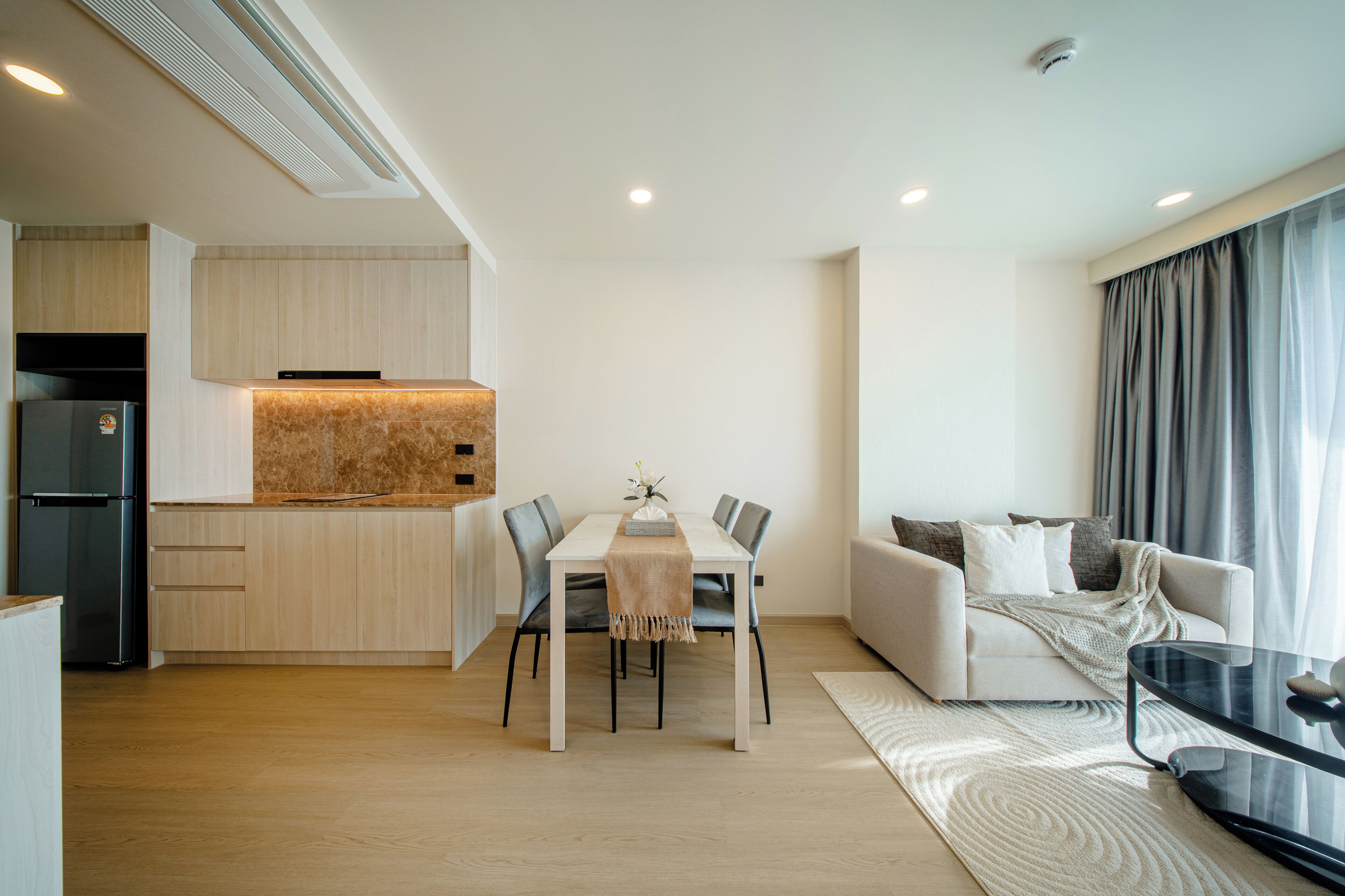 A modern living space with a dining area, kitchen, and seating area.