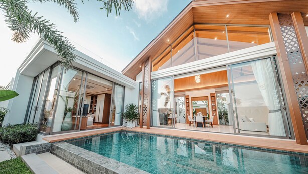 A modern house with a swimming pool, large glass windows, and a wooden interior. - The Ozone Residences Bangtao (Choeng Thale)