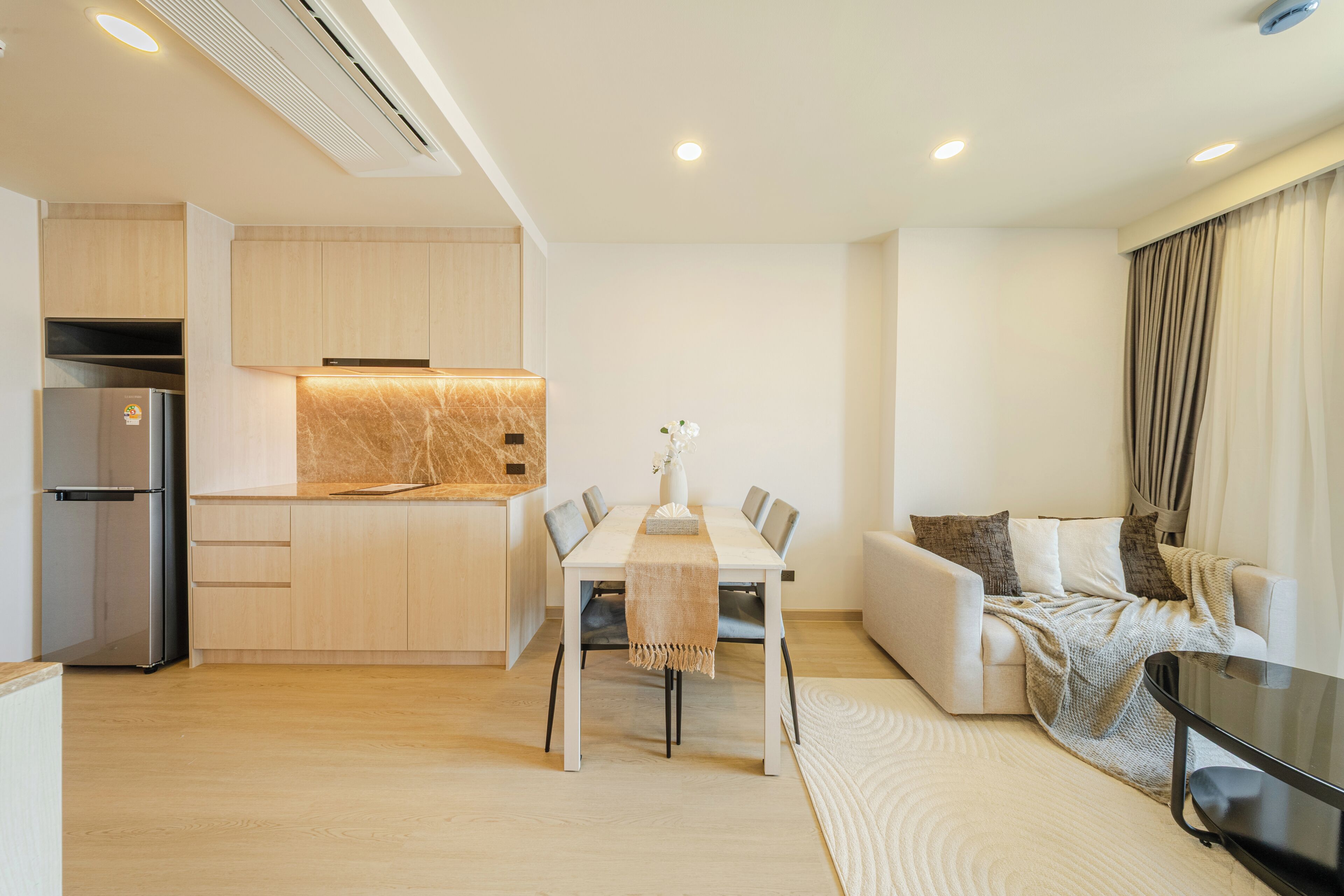 A modern living space with a dining area, kitchen, and seating area.