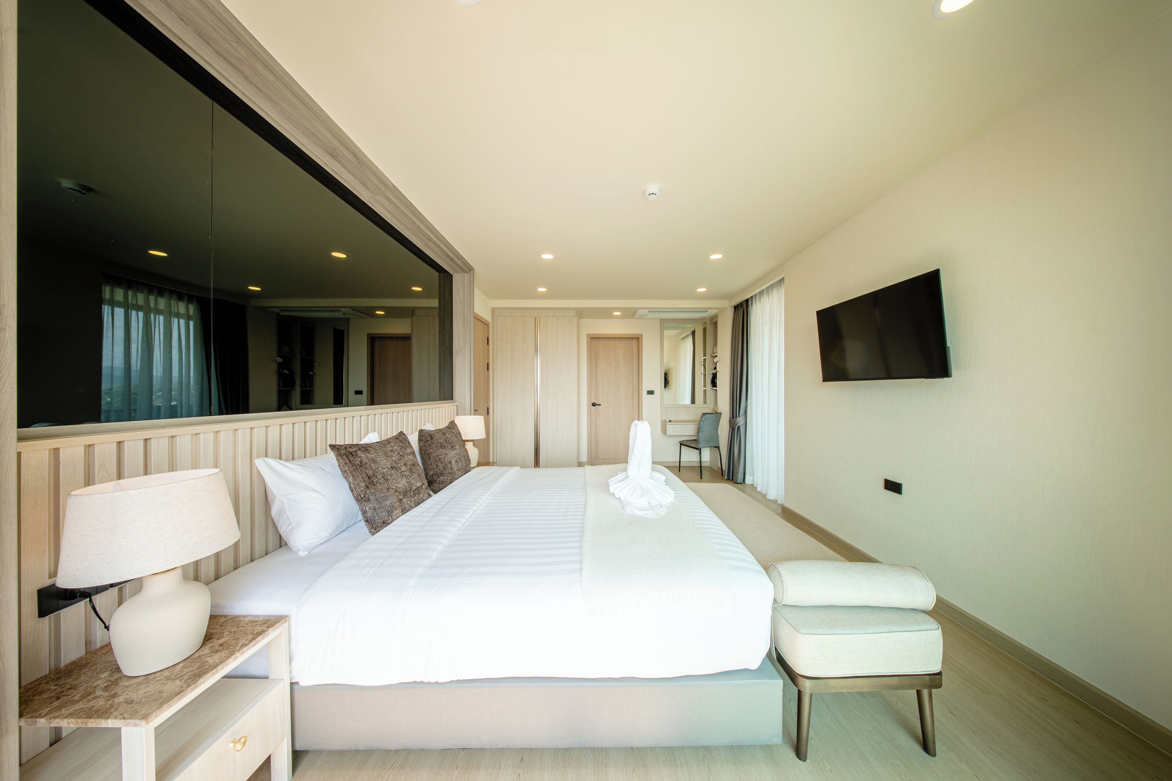 A hotel room with a large bed, bedside tables, a flat-screen TV, and a mirror.